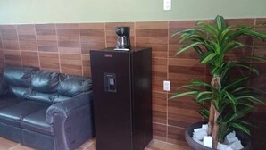 A room with a black leather sofa, a black refrigerator, and a potted plant. - Estancia La Quinta María 2 (Veracruz)