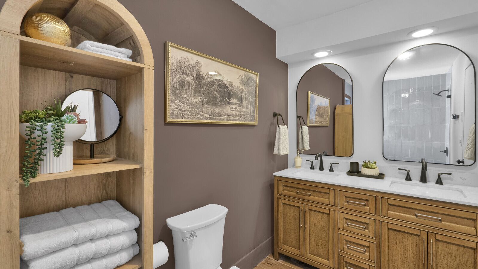 Un bagno con un mobile lavabo in legno, due lavabi e un water. Sul mobile si trovano asciugamani e una pianta in vaso.