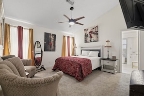 A hotel room with a bed, a chair, a nightstand, a mirror, and a ceiling fan. - Gorgeous 4-bedroom duplex with AC in tranquil Richardson (Richardson)