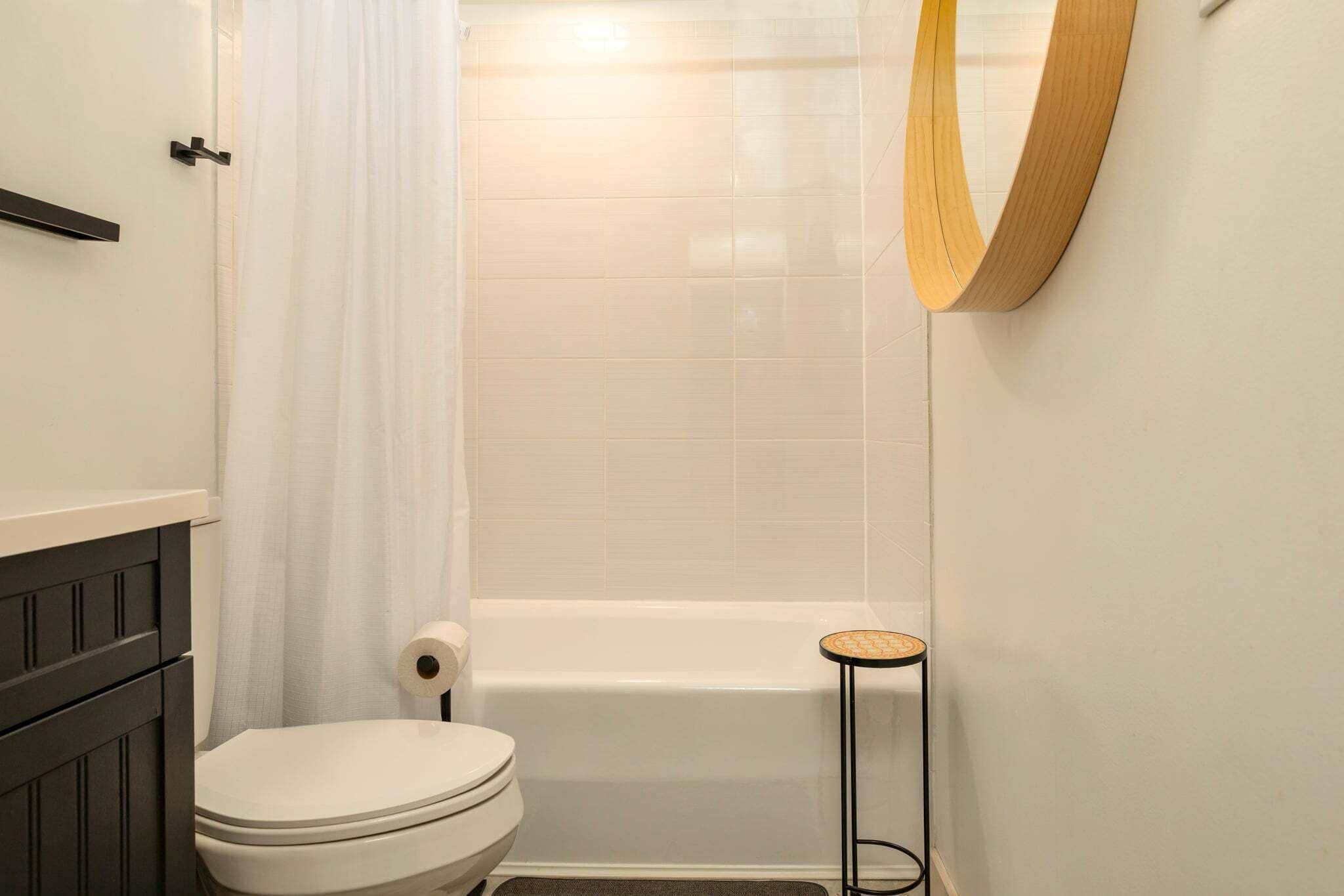 Et badeværelse med toilet, badekar og et lille rundt bord.