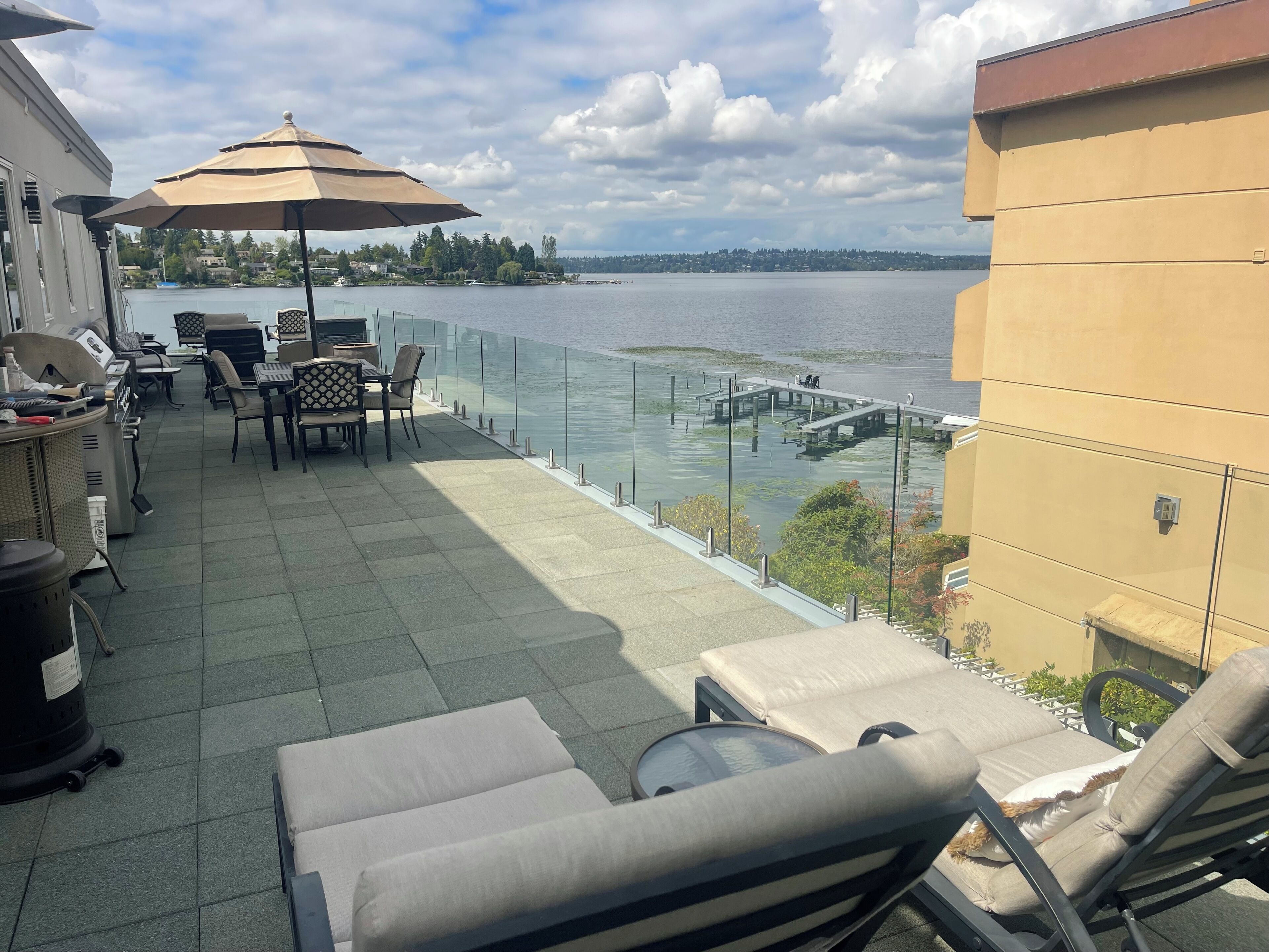 Ein Balkon mit Gartenmöbeln, einer Glasbrüstung und Blick auf einen See.