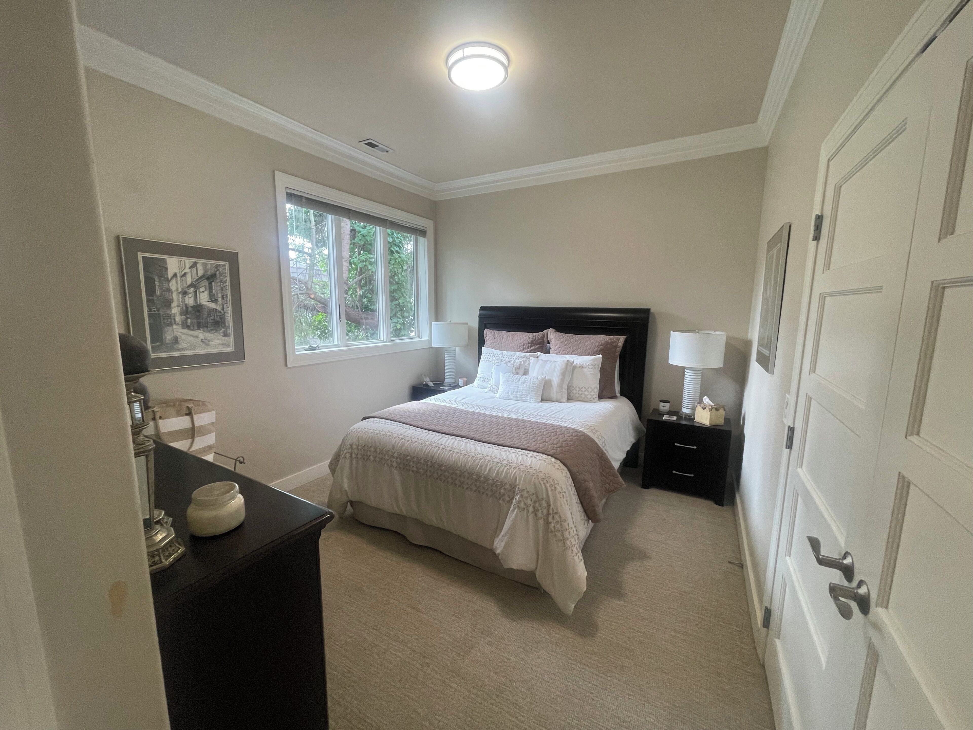 A bedroom with a bed, bedside tables, a window, and a door.