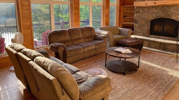A cozy living room with a stone fireplace, large windows, and comfortable seating. - Pet Friendly Luxury Cottage (Dysart Et Al)