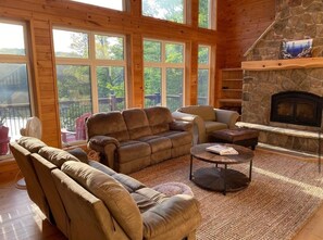 A cozy living room with a stone fireplace, large windows, and comfortable seating. - Pet Friendly Luxury Cottage (Dysart Et Al)