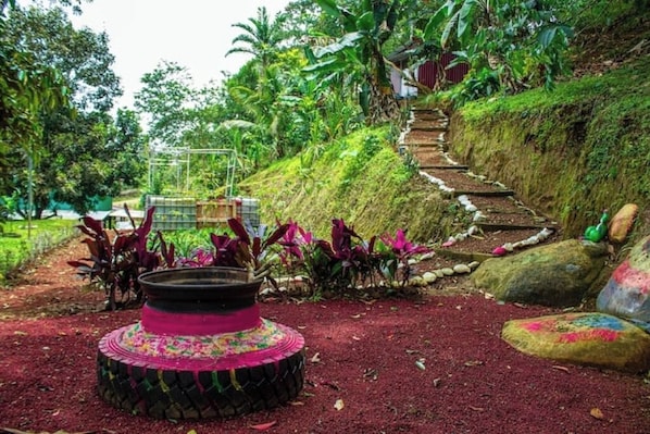 A garden with a decorative circular structure, a stone pathway, and lush greenery.