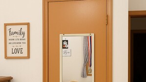Eine Tür mit einem Spiegel, der einen Hund auf einem Bett zeigt. Ein gerahmtes Zitat an der Wand trägt die Aufschrift "Family WHEELS LITE BECAUSE AND LOVE.NG TEN THIS LOVE".