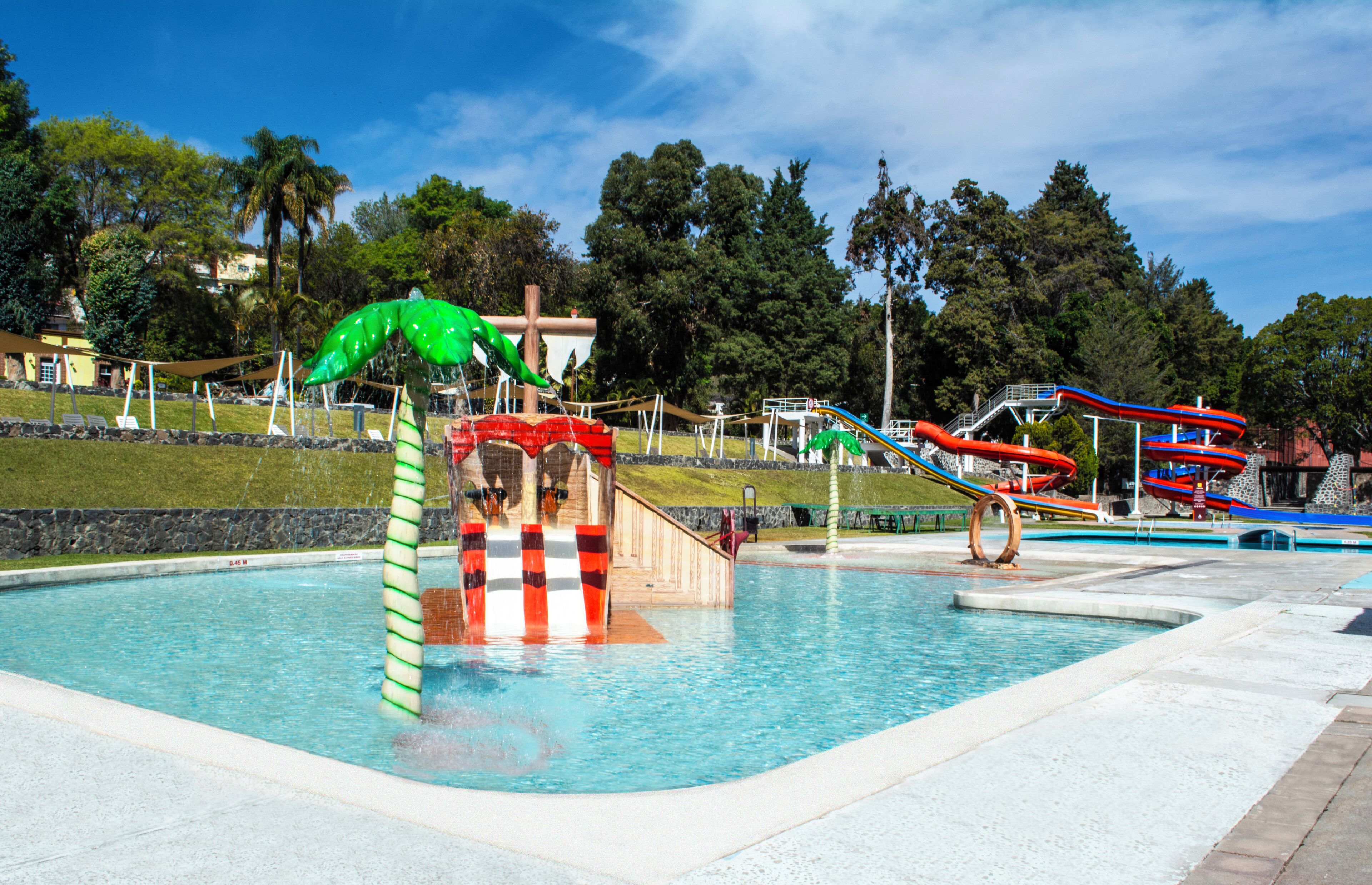 A water park with a pool, slides, and a green inflatable structure.