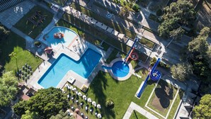 Vue aérienne d’un complexe hôtelier doté d’une grande piscine, d’un toboggan aquatique et d’espaces de détente en plein air.