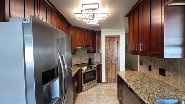 A modern kitchen with wooden cabinets, stainless steel appliances, granite countertops, and a built-in oven. - A&C WINDWARD COTTAGE # 2 (Victoria)