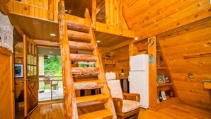 A wooden cabin interior with a wooden staircase, a white refrigerator, and a dining table with chairs. - Pet friendly off grid chalet tucked away on a mountainside . (Sandpoint)