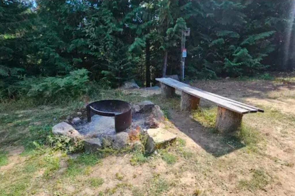 Un hogar rodeado de rocas y un banco de madera en un área boscosa.