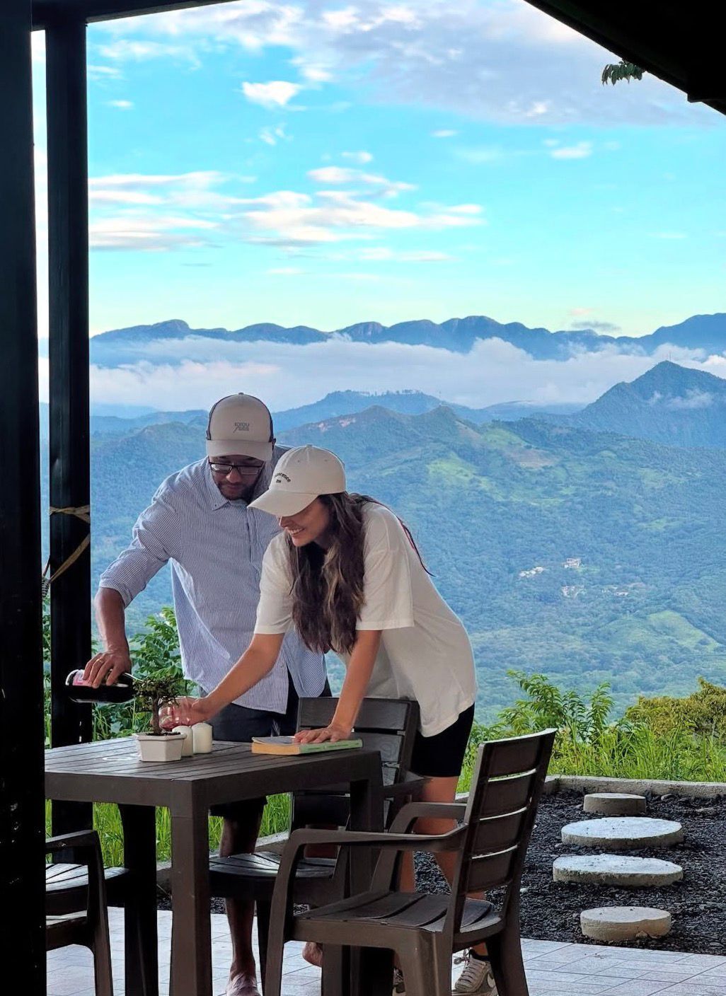 Zwei Personen sitzen an einem Tisch im Freien mit einem malerischen Bergblick im Hintergrund.