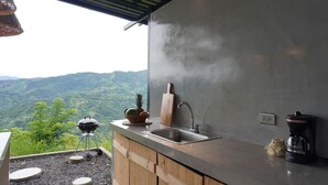 Une cuisine avec vue sur les montagnes, un barbecue, un évier et une machine à café.