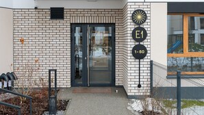 Moderni rakennus, jossa on tiiliverhous, lasinen sisäänkäynti ja kyltti, jossa on osoite.