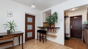 Une pièce avec un bureau en bois, une chaise, une bibliothèque, une plante en pot et une porte en bois foncé.