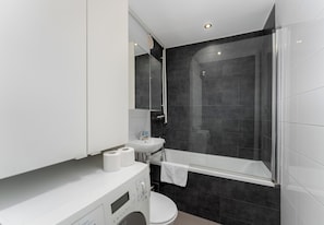 A modern bathroom with a white sink, toilet, and a glass-enclosed shower. - Odrzańska Urban Jungle Apartment (Kraków)