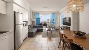 Eine moderne Küche mit integriertem Kühlschrank, einem Essbereich mit Holztisch und -stühlen sowie einem großen Fenster mit Blick auf die Stadt.