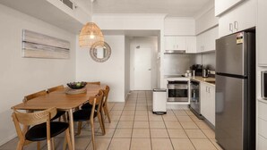 Eine moderne Küche mit weißen Schränken, einem Edelstahl-Kühlschrank und einem Essbereich mit Holztisch und Stühlen.
