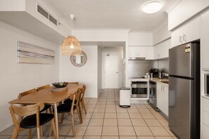 Eine moderne Küche mit weißen Schränken, einem Edelstahl-Kühlschrank und einem Essbereich mit Holztisch und Stühlen.