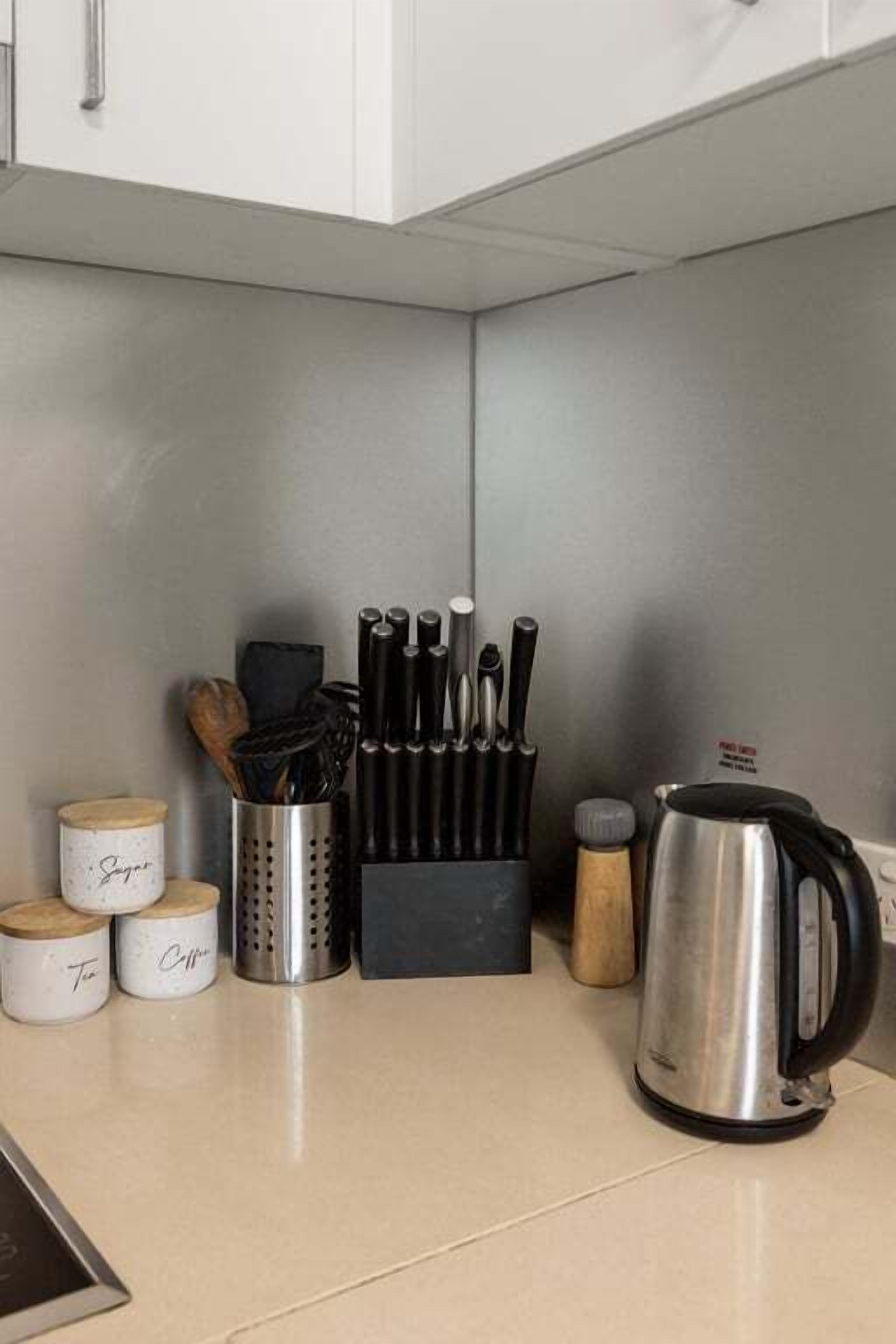 A kitchen counter with a knife block, a kettle, and spice jars.