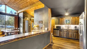 Una cocina moderna con armarios de madera, un refrigerador de acero inoxidable y un amplio ventanal con vistas a un paisaje nevado.