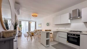 Une cuisine moderne dotée d’un îlot central, d’un coin repas avec des chaises et d’une grande fenêtre.