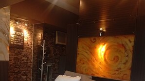 A modern bedroom with a stone accent wall, a large bed with white bedding, and a unique wall art piece. - The Gold Leaf Getaway: Stylish 1BR Urban Oasis (Taguig)