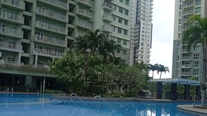 A residential building with balconies, a swimming pool, and surrounding greenery. - The Gold Leaf Getaway: Stylish 1BR Urban Oasis (Taguig)
