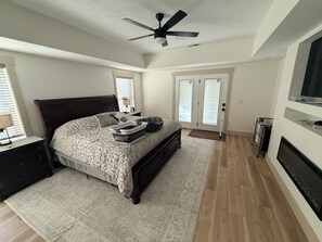 A bedroom with a bed, a ceiling fan, a dresser, a TV, and a sliding glass door. - Lake Cumberland Lake House! We would love to share our retirement home with you! (Monticello)