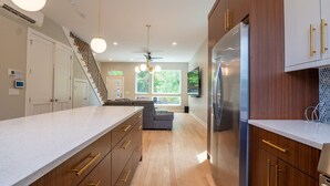 Une cuisine moderne avec des meubles en bois, un réfrigérateur en acier inoxydable et un grand îlot central doté de poignées dorées.