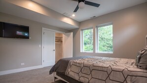 Une chambre à coucher avec un lit, un ventilateur de plafond, une télévision et un placard.