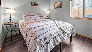 Een slaapkamer met een bed, twee bedlampen, een raam met uitzicht en een aan de muur hangend schilderij.