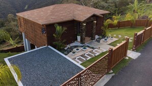 A modern house with a stone facade, a wooden deck, and a view of the surrounding hills.