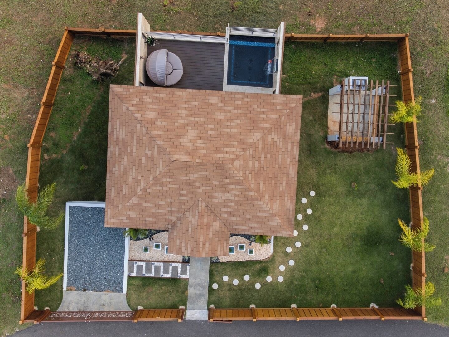 Vue aérienne d’une cour arrière avec une terrasse, une piscine et une plateforme en bois.