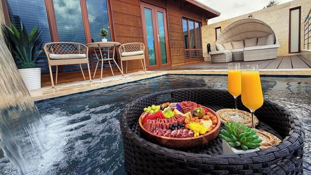 A poolside area with a hot tub, wicker furniture, and a fruit and cheese platter.