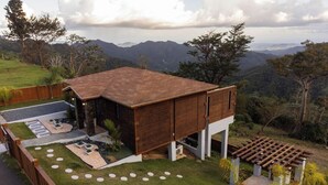 A modern house with a wooden exterior, a spacious backyard, and a view of the surrounding hills.