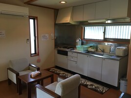 Una cocina funcional con estufa, lavamanos y un pequeño comedor con mesa y sillas.