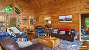 Ein gemütliches Holzhaus-Interieur mit Essbereich, Kamin und Couchtisch.