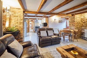 A cozy living room with a leather sofa, wooden coffee table, and a dining area with wooden chairs and a table. - Host Stay Mill House Brid (Bridlington)