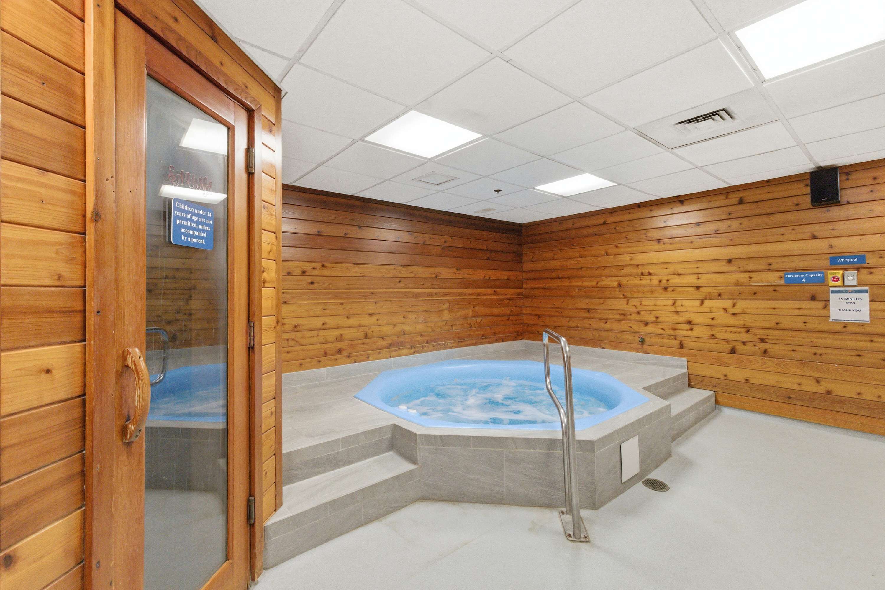 Una habitación con paneles de madera, un jacuzzi y una puerta de vidrio.