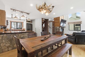 A spacious kitchen with a large wooden table, stone countertop, and a unique antler chandelier. - Mountain Views & Luxury Lodge Living Next to Loon (Lincoln)