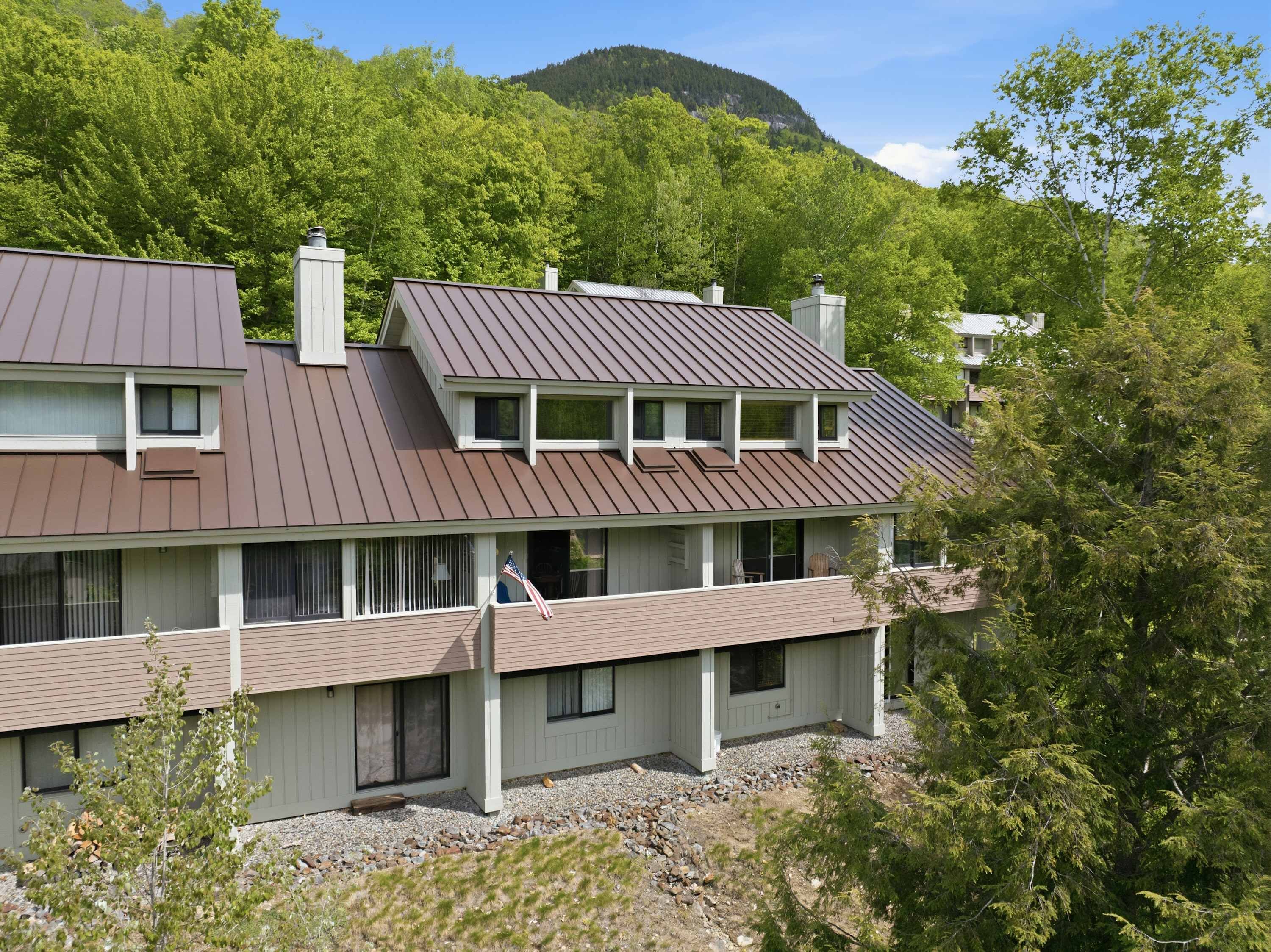 A two-story building with a sloped roof, multiple windows, and a balcony.