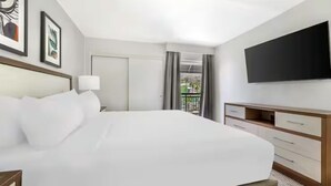 Une chambre d’hôtel avec un grand lit, une télévision, un bureau et un balcon avec des rideaux.