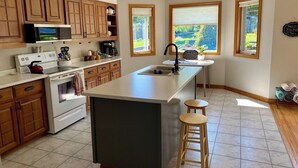 Una cocina con armarios de madera, una isla grande, un microondas, una estufa y un lavabo.