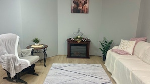 Un salón con sofá, una silla, una mesita con planta, una estrella decorativa y una chimenea.