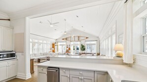 Uma cozinha espaçosa com armários brancos, uma ilha grande e uma área de refeições com vista.