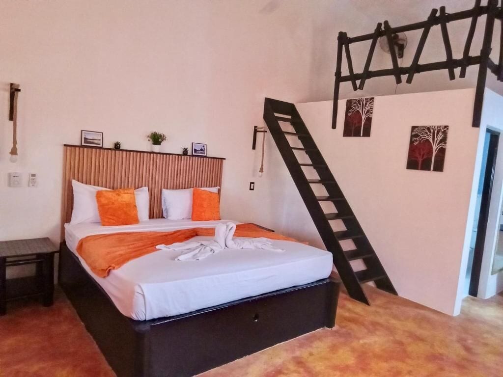 Ein Schlafzimmer mit einem Bett, einem Holzkopfstück, einer an der Wand stehenden Leiter und gerahmten Bildern.