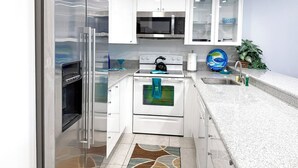 Een moderne keuken met witte kastjes, roestvrijstalen apparatuur en een granieten aanrecht.