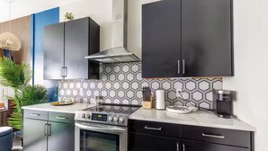 A modern kitchen with stainless steel appliances, black cabinets, and a geometric tile backsplash. - Jungle Fun House, Karaoke, Minutes to Broadway (Nashville)