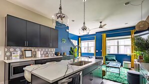 A modern kitchen with dark cabinets, a marble island, and a blue accent wall. - Jungle Fun House, Karaoke, Minutes to Broadway (Nashville)